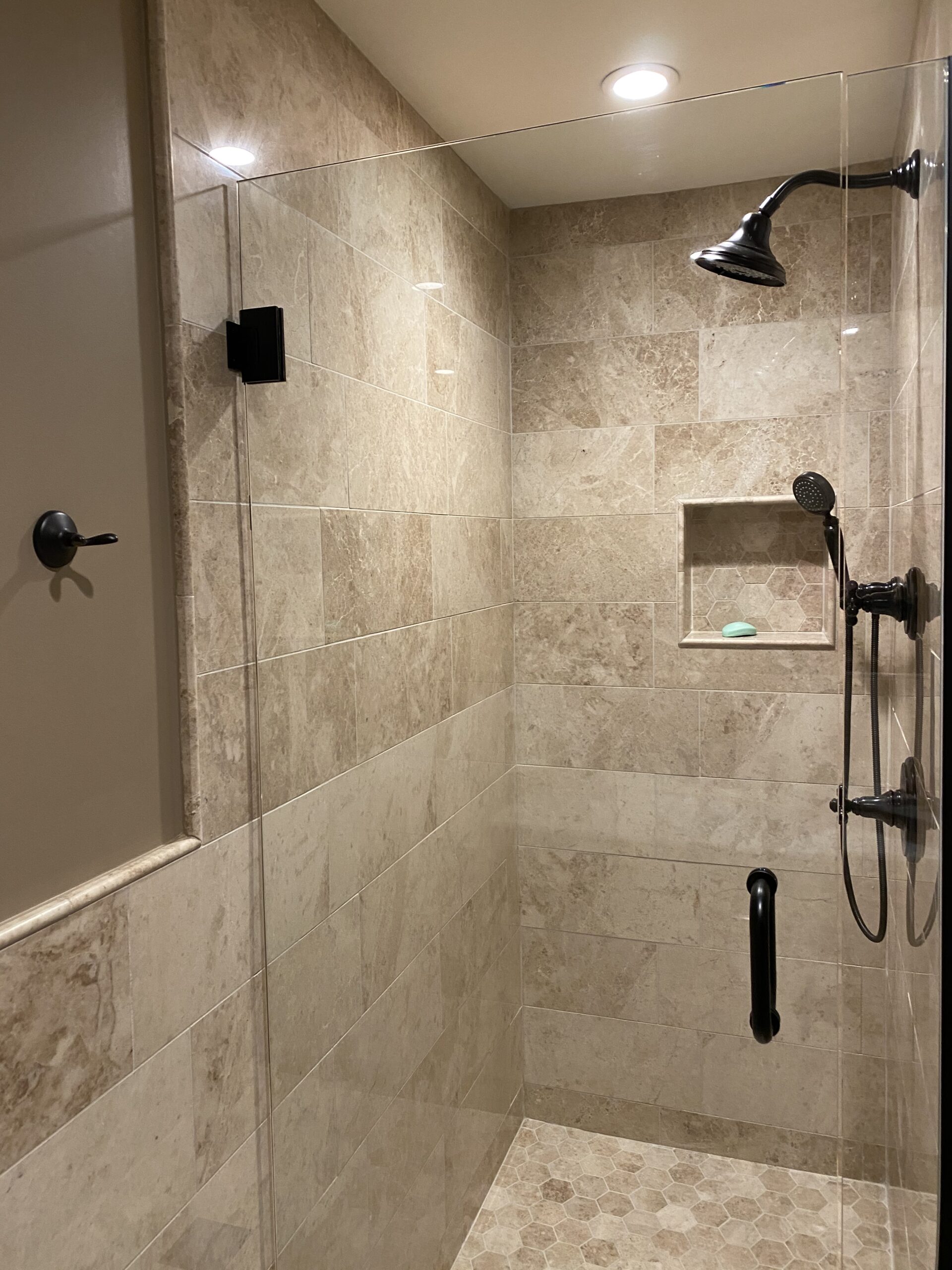 Shower with rectangular tiles, space for bottles, and two shower heads